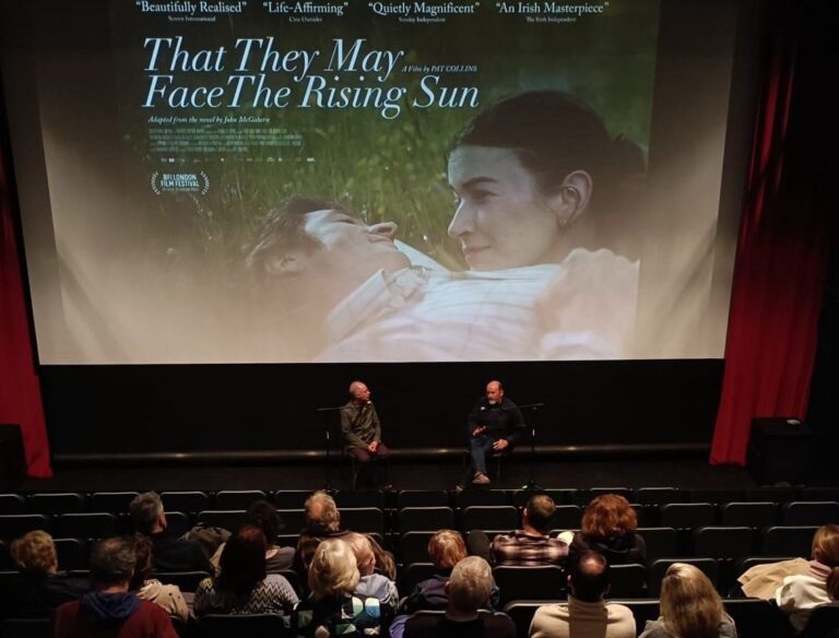 Filmmaker Pat Collins speaking during a Q&A at Source Arts Centre, with the poster image of That They May Face The Rising Sun displayed behind him